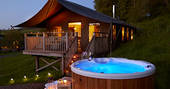 The Tamar safari tent at dusk with a glowing hot tub